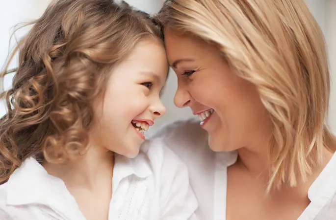 Madre e hija sonriendo, símbolo de la odontología para adultos y niños de la Clínica Herena Díez