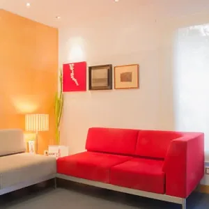 Sala de espera de la Clínica Herena Díez con sofás en rojo y gris