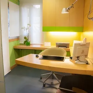 Consulta de la Clínica Herena Díez con mobiliario en madera y una orquídea